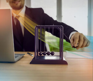Business professional at desk with laptop and Newton’s cradle symbolizing reability and uptime